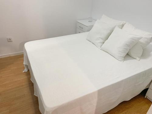 a bed with white sheets and pillows in a room at Apartamento Centro Costa de la Luz in Sanlúcar de Barrameda