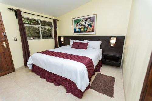a bedroom with a large white bed with red pillows at Park Hotel in Santa Cruz Verapaz