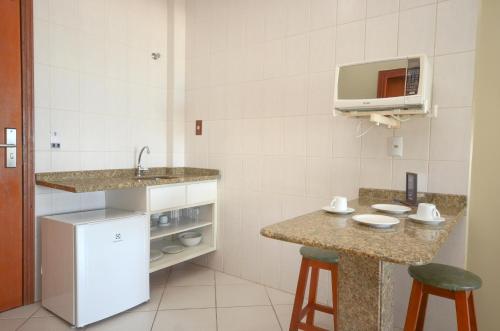 eine Küche mit einer Spüle und einer Theke mit Hockern in der Unterkunft Pousada Garatéia in Bombinhas