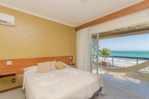 1 dormitorio con 1 cama y balcón con vistas al océano en Pousada Garatéia, en Bombinhas