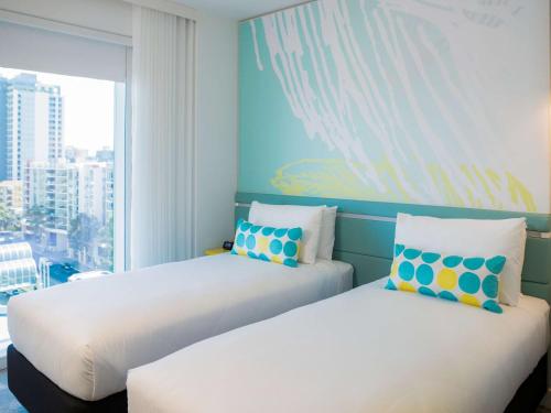 two beds in a room with a large window at ibis Styles East Perth in Perth