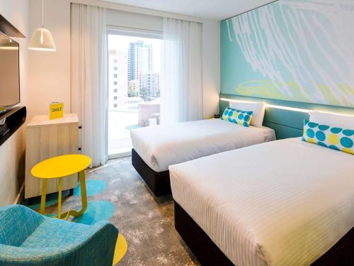 a hotel room with two beds and a chair at ibis Styles East Perth in Perth