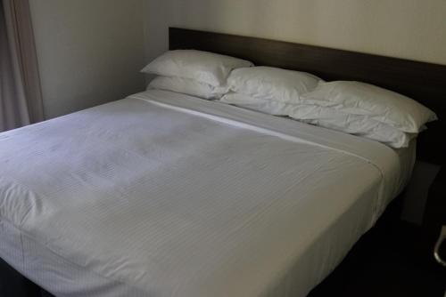 a neatly made bed with white sheets and pillows at Reef Resort Villas Port Douglas in Port Douglas