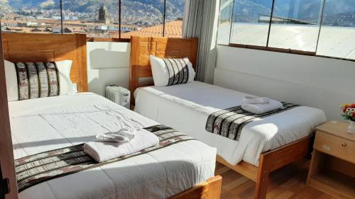 two beds in a room with a window at Cusco Hostal Qolla Wasi in Cusco