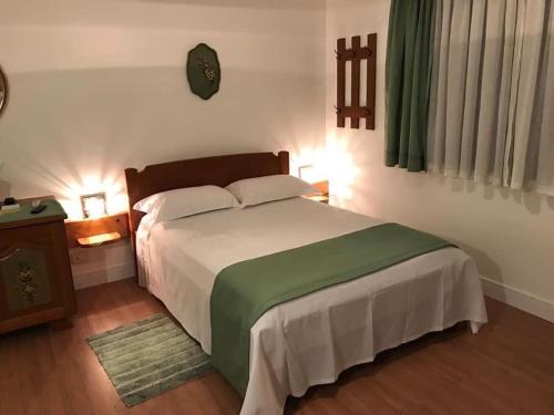 a bedroom with a large white bed with a green blanket at Hospedaria Haus Scharf in Treze Tílias
