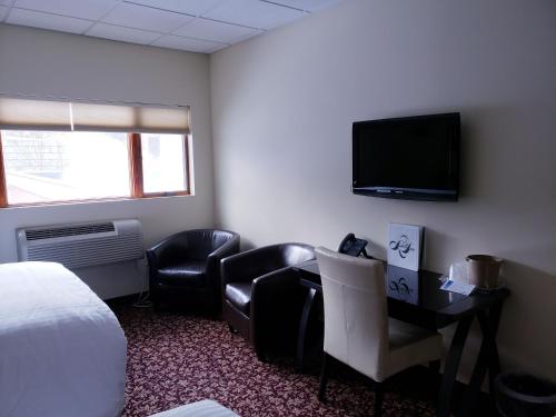 a hotel room with a bed and a desk and a tv at Lowell Inn in Stillwater