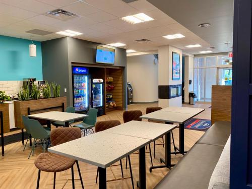 eine Cafeteria mit Tischen, Stühlen und einer Soda-Maschine in der Unterkunft Howard Johnson by Wyndham Winnipeg West in Winnipeg