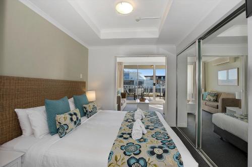 a bedroom with a large bed and a living room at Ettalong Beach Luxury Apartments in Ettalong Beach