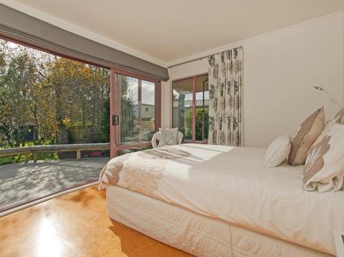 a bedroom with a large bed and a large window at Carefree at Cooks - Cooks Beach Bach in Cooks Beach