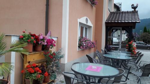 un patio con mesas, sillas y flores en un edificio en Pension Kirchsteiger en Hohenberg