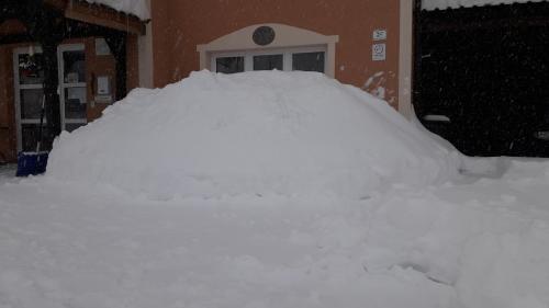 een berg sneeuw aan de zijkant van een huis bij Pension Kirchsteiger in Hohenberg