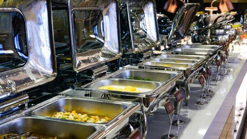 a row of stainless steel trays of food at Paco Hotel BeiJing Road Metro Guangzhou-Free Shuttle Bus For Canton Fair in Guangzhou
