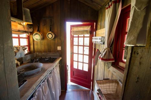 - une cuisine avec un évier et une porte rouge dans l'établissement Hébergements Insolites dans tonneaux - Gite Le Coup de Foudre, à Vimoutiers