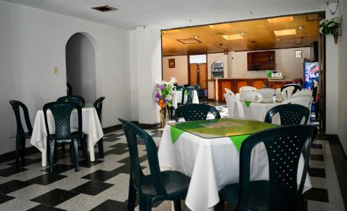 un comedor con mesas blancas y sillas verdes en Hotel Venecia Confort, en Pasto