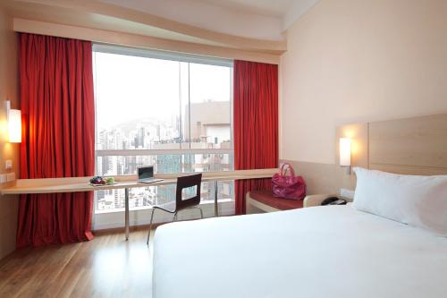 a hotel room with a bed and a desk and a window at Ibis Hong Kong Central & Sheung Wan in Hong Kong