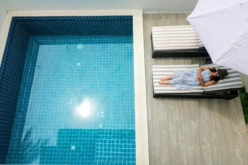 un hombre y una mujer acostados en las camas junto a una piscina en Samui Blue Orchid - Adult Only, en Choeng Mon Beach