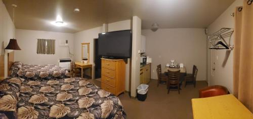 1 dormitorio con cama, mesa y comedor en Sunset Motel, en Fort Macleod