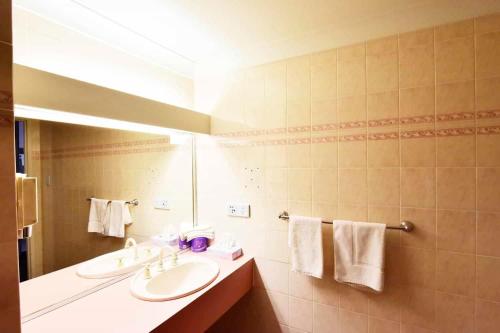 een badkamer met 2 wastafels, een spiegel en handdoeken bij Diplomat Hotel Alice Springs in Alice Springs