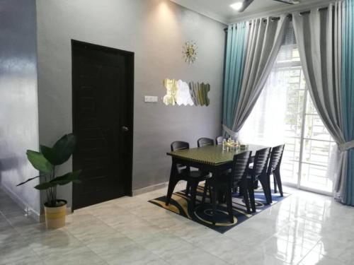 a dining room with a black table and chairs at Damai D Homestay in Kangar