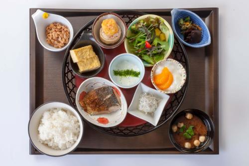 尾道市にある尾道ロイヤルホテルのテーブルの上に様々な種類の食料を詰めたトレイ