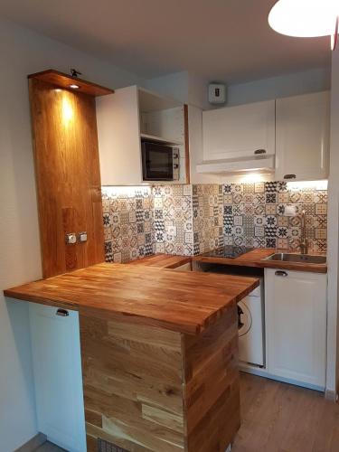 une cuisine avec des armoires blanches et un comptoir en bois dans l'établissement T2 Bandol idéal vacances 2 étoiles, à Bandol