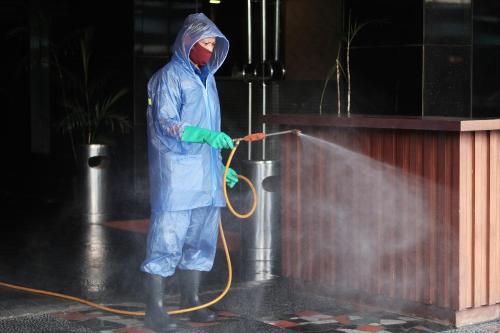 a person in a raincoat andmask holding a hose at The BluEco Hotel SHA Plus in Kata Beach