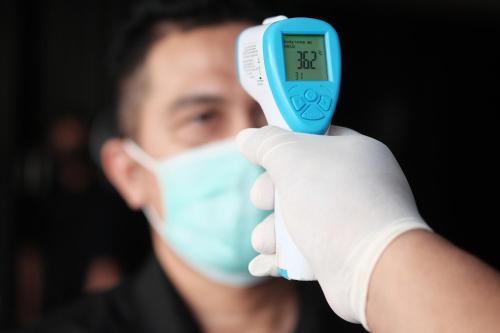 a man wearing a mask holding a temperature thermometer at The BluEco Hotel SHA Plus in Kata Beach