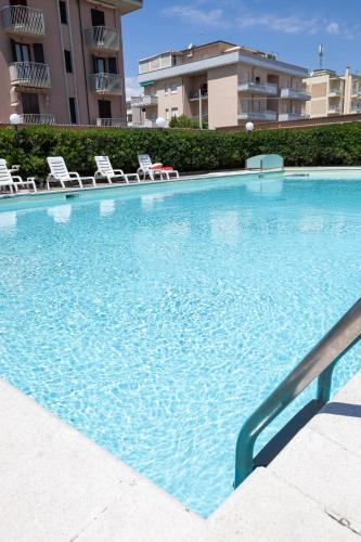a large swimming pool with chairs and a building at Hotel Primavera sul mare in Lido di Savio