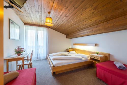 a bedroom with a large bed and a wooden ceiling at Hotel Pension Rechtenthal in Termeno
