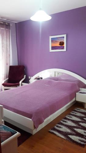 a purple bedroom with a bed and a chair at House Fox in Iraklitsa