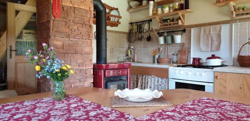 Il comprend une cuisine équipée d'une cuisinière et d'une table avec un vase de fleurs. dans l'établissement MOUNTAIN ECO CHALET KONJSKA DOLINA on 1400 m asl -near Pokljuka, à Srednja Vas v Bohinju