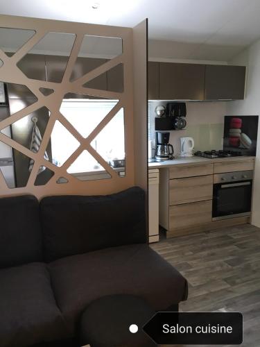 un salon avec un canapé et une cuisine dans l'établissement Mobilhome LAME, à Gastes