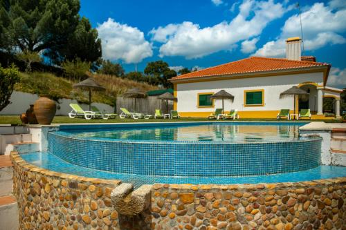 a swimming pool with a house in the background at Vale De Ferreiros in Abrantes