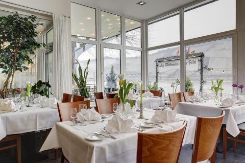 a restaurant with white tables and chairs and windows at Lindenhof in Osterspai