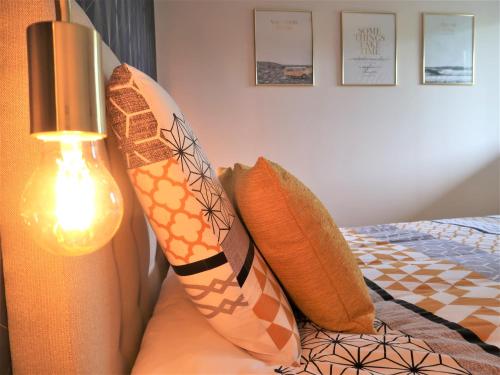 - un lit avec des oreillers et une lampe dans l'établissement Appart'Confort - Le Trégor, à Lannion