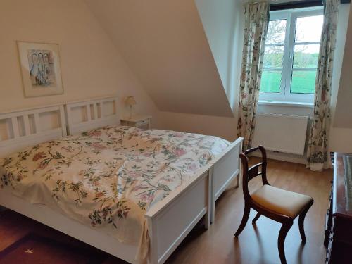 a bedroom with a bed and a chair and a window at Forsthof Schlemmin in Eickhof