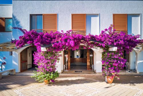 a building with purple flowers in front of it at Blu Salento Village in Sant'Isidoro