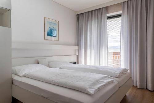 een witte slaapkamer met een groot bed en een raam bij Ferienwohnung Sabolowitsch in Lam