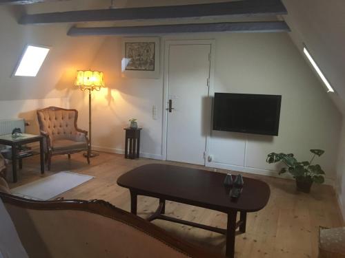 uma sala de estar com uma televisão, um sofá e uma mesa em Den Gamle Arrest em Ribe