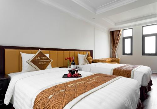 two beds in a hotel room with flowers on a table at An Ph&uacute; Hạ Long Luxury Hotel in Ha Long