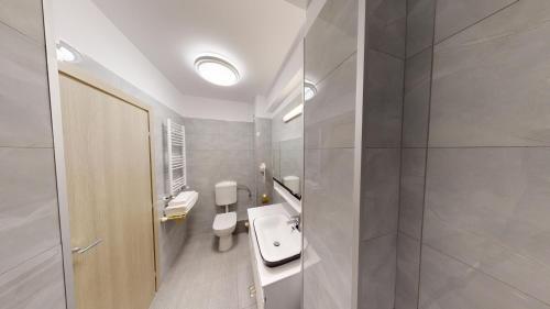 a bathroom with a white toilet and a sink at Le Blanc ApartHotel in Bucharest