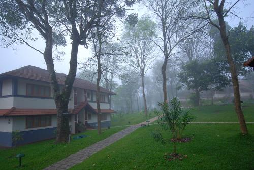 a house with a walkway next to a yard with trees at Greenwoods Resort, Thekkady in Thekkady