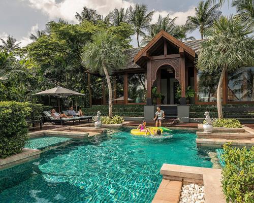 a family playing in a pool at a resort at Four Seasons Resort Koh Samui in Mae Nam