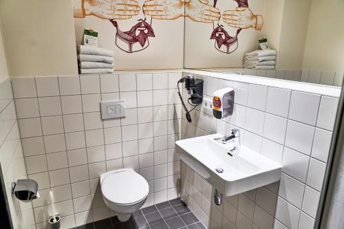a white toilet sitting next to a white sink at McDreams Hotel München - Messe in Feldkirchen