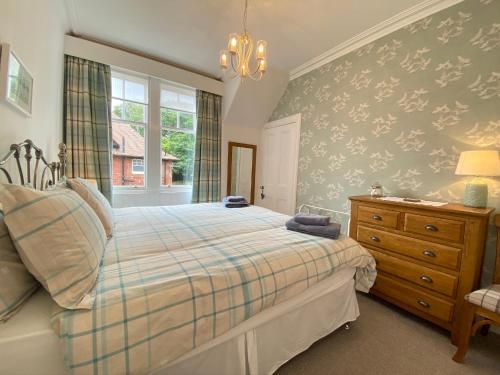 a bedroom with a bed and a dresser and a window at Old Abbey Cottage in North Berwick