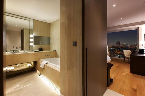 a bathroom with a tub and a sink and a mirror at Hotel Entra Gangnam in Seoul