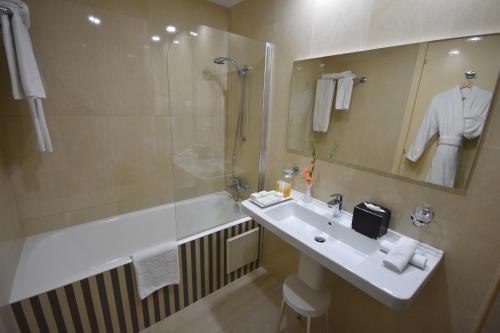uma casa de banho com um lavatório, um chuveiro e uma banheira em Ramada Plaza by Wyndham Tunis em Gammarth