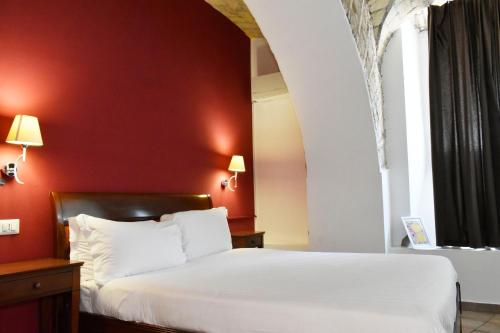 a bedroom with a white bed and a red wall at Roma Resort Colosseum in Rome