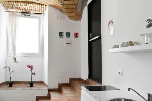 a kitchen with white walls and a staircase with a window at Roma Resort Colosseum in Rome