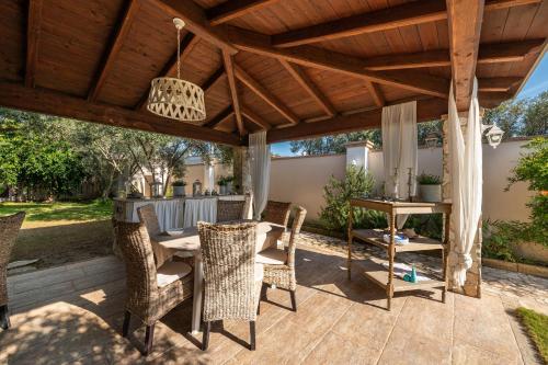 a patio with a table and chairs under a wooden pergola at Villa Maria Beatrice in Quartu SantʼElena